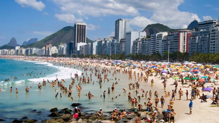 Praia de Copacabana com águas claras e pessoas se divertindo, ideal para banho.