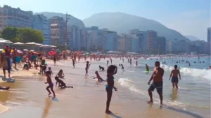 Vista da praia de Ipanema, famosa por ser boa para banho, com pessoas aproveitando o dia ensolarado.