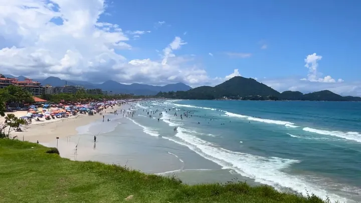 Vista da praia de Ubatuba com céu azul e vegetação exuberante