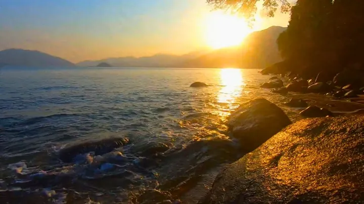Pôr do sol em Ubatuba com céu alaranjado e silhueta das montanhas