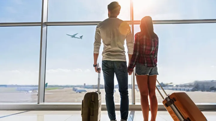 Pessoa planejando viagem com milhas aéreas usando laptop e blocos de notas