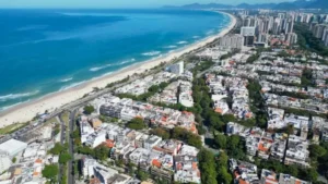 Vista aérea da Barra da Tijuca com prédios, casas e praia ao fundo.