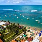 Vista aérea de praia com barracas e barcos no mar em Porto de Galinhas