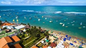 Vista aérea de praia com barracas e barcos no mar em Porto de Galinhas