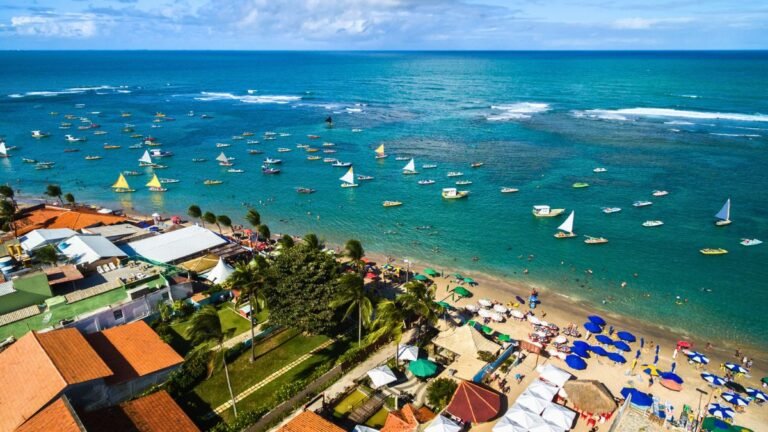 Vista aérea de praia com barracas e barcos no mar em Porto de Galinhas