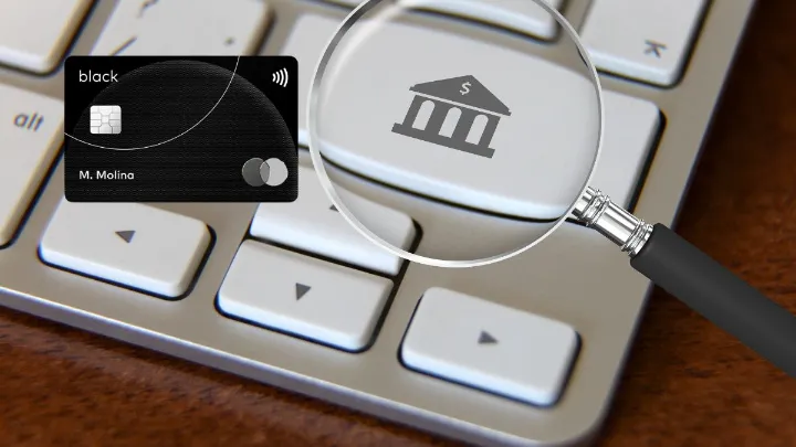 Cartão Mastercard Black e lupa com ícone de banco sobre teclado.