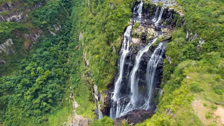 Vista a&eacute;rea do C&acirc;nion Fortaleza em Cambar&aacute; do Sul com cachoeiras descendo entre pared&otilde;es verdes e mata nativa.